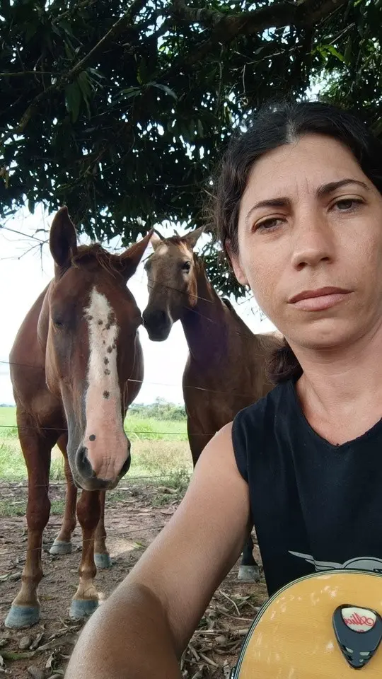Lôids no campo, com o violão, em frente a dois cavalos