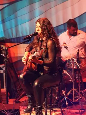 Lôids cantando com o violão, acompanhada de percussão
